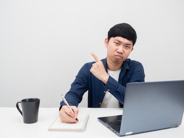 Uomo asiatico che lavora sul posto di lavoro annoiato e punta il dito contro lo spazio della copia