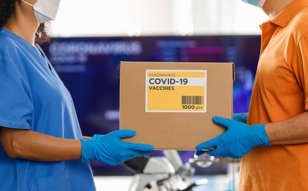 Uomo asiatico che maneggia una scatola di vaccino Covid 19 per un'infermiera asiatica in ospedale. Concetto per la vaccinazione contro il Covid 19.