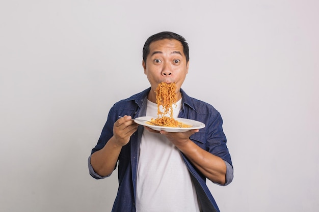 Uomo asiatico che mangia un sacco di spaghetti istantanei e si sorprende di quanto sia delizioso