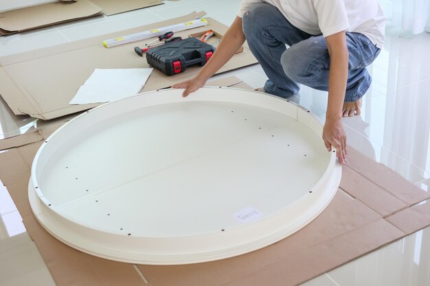Uomo asiatico che monta mobili da tavola bianchi a casa