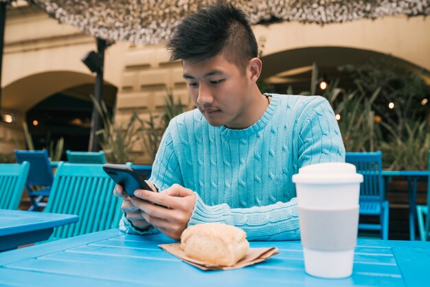 Uomo asiatico che per mezzo del suo telefono cellulare.