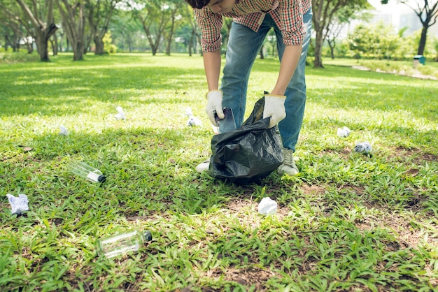 Uomo asiatico che raccoglie rifiuti domestici di plastica nel parco