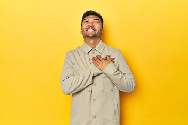 Uomo asiatico che ride tenendo le mani sul cuore concetto di felicità