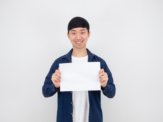 Uomo asiatico che tiene carta vuota con un sorriso felice in faccia su sfondo bianco