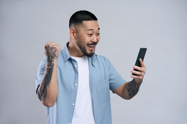 Uomo asiatico che tiene la comunicazione del telefono cellulare online con una videochiamata isolata su sfondo grigio