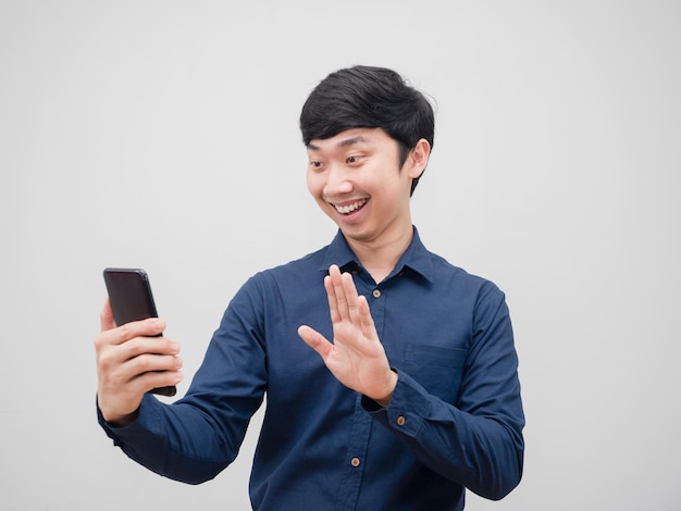 Uomo asiatico che tiene la videochiamata del telefono cellulare con emozione felice e sorriso su fondo bianco