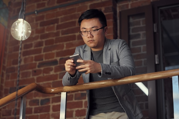 Uomo asiatico che usando Smartphone al balcone