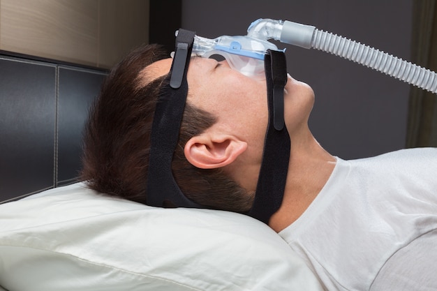 Uomo asiatico con apnea del sonno con macchina CPAP