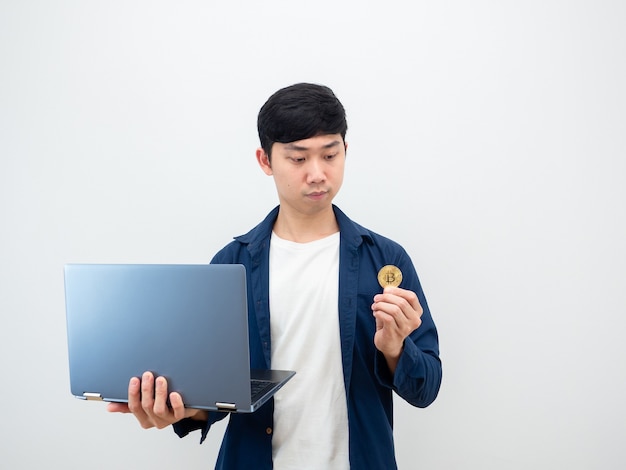 Uomo asiatico con laptop e guardando bitcoin in mano su sfondo bianco denaro digitale concept