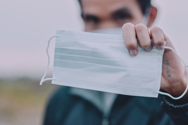 Uomo asiatico con maschera facciale, maschera chirurgica per proteggere corona virus covid 19