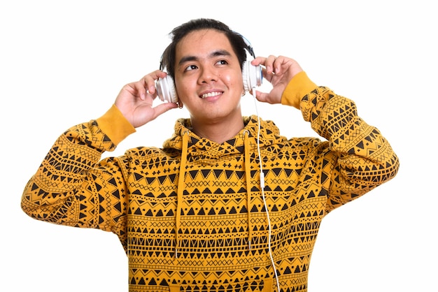 Uomo asiatico felice premuroso che sorride mentre ascolta la musica