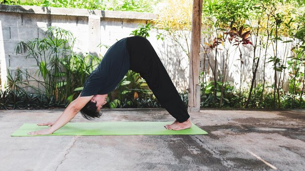 Uomo asiatico in abbigliamento casual che pratica yoga nella posa del cane rivolta verso il basso Concetto di vita sana