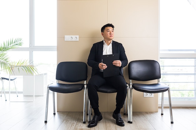 uomo asiatico in attesa di un colloquio di lavoro nella sala d'attesa del centro uffici