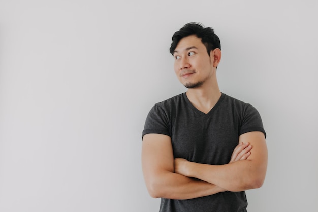 Uomo asiatico in maglietta nera che incrocia le braccia isolato sul bianco