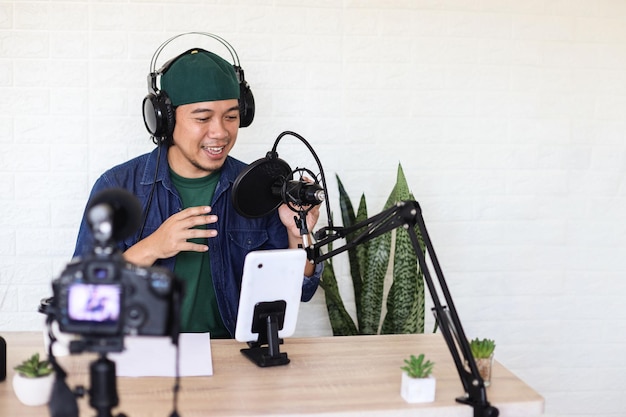 Uomo asiatico in stile casual che parla in podcast a casa studio