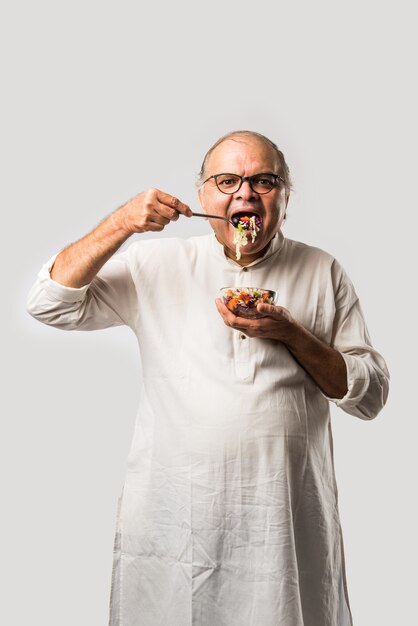 Uomo asiatico indiano senior che mangia insalata verde fresca. Maschio maturo maschio che mangia spuntino sano, assistenza sanitaria, concetto di dieta