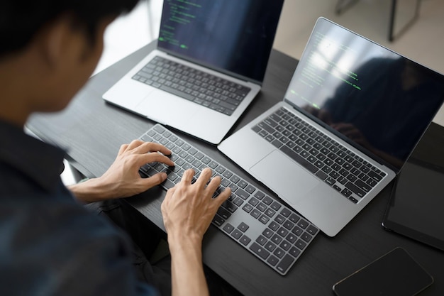 Uomo asiatico ingegnere software Lavora al computer alla scrivania dell'ufficio per scrivere codice di programmazione IT Ingegnere software che trova errori supporto tecnico devops che crea digitale