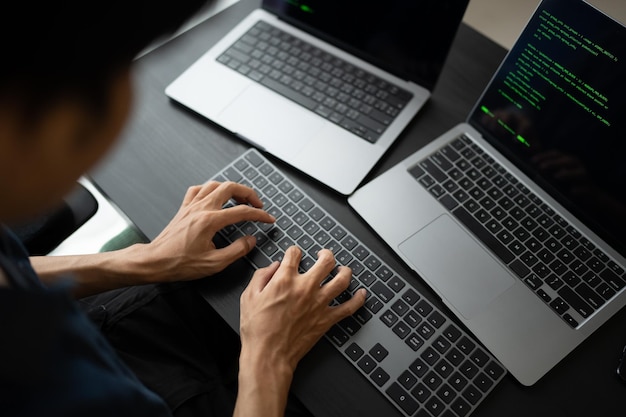 Uomo asiatico ingegnere software Lavora al computer alla scrivania dell'ufficio per scrivere codice di programmazione IT Ingegnere software che trova errori supporto tecnico devops che crea digitale