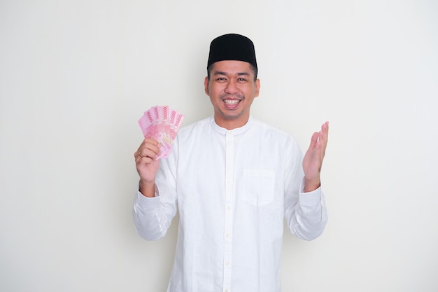 Uomo asiatico musulmano che mostra gesto grato mentre tiene carta moneta
