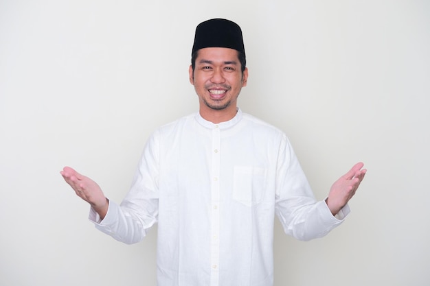 Uomo asiatico musulmano sorridente felice di salutare durante la celebrazione del Ramadan con entrambe le braccia aperte