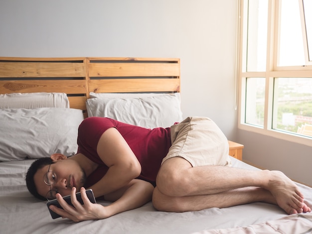 Uomo asiatico non sociale solitario con il suo smartphone nel suo appartamento.