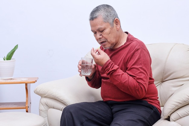 Uomo asiatico senior che prende la pillola della medicina a casa