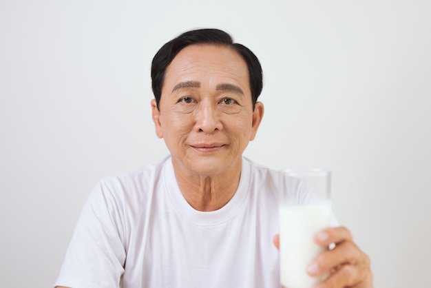 Uomo asiatico senior che tiene un bicchiere di latte