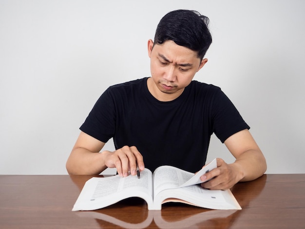 Uomo asiatico seriamente sulla lettura del libro di testo per la prova sul tavolo