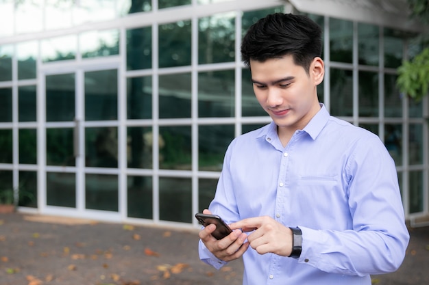 Uomo asiatico sorridente felice di affari all&#39;aperto con lo Smart Phone