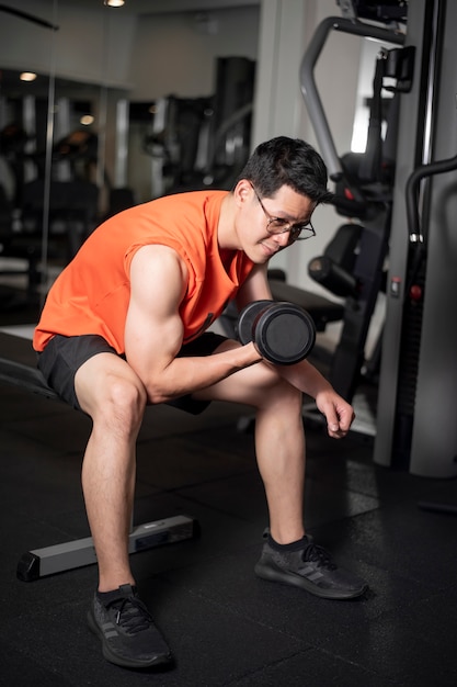 Uomo asiatico sta lavorando in palestra