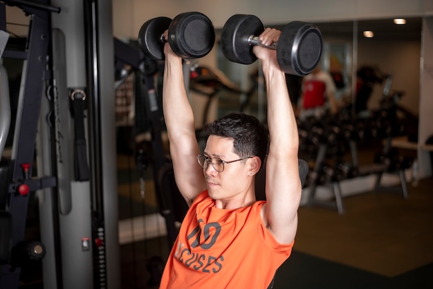 Uomo asiatico sta lavorando in palestra