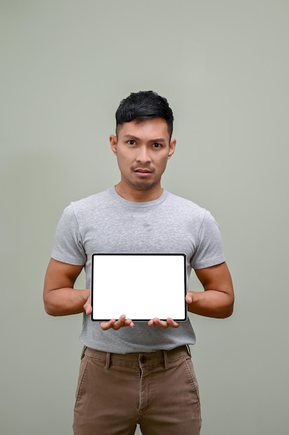 Uomo asiatico stressato e serio che tiene un modello di tablet isolato sfondo verde