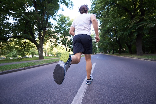 uomo atleta sano che fa jogging al mattino su strada vuota in città