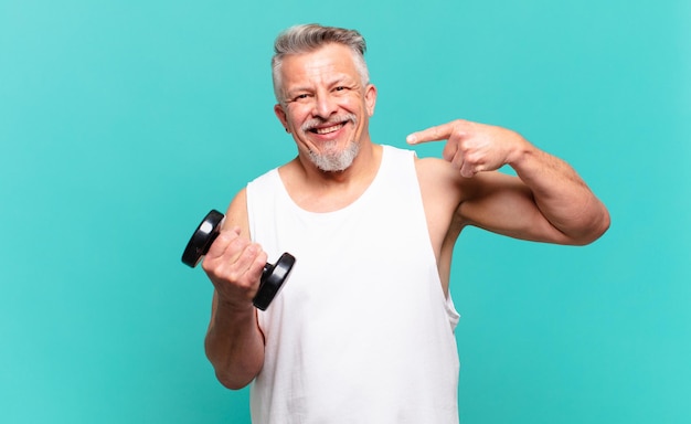 Uomo atleta senior che sorride con sicurezza indicando il proprio ampio sorriso, atteggiamento positivo, rilassato e soddisfatto