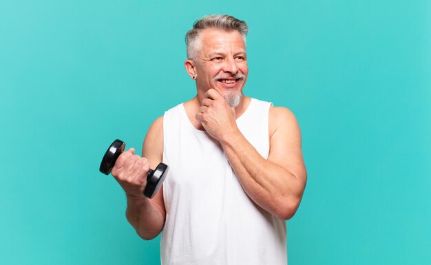 Uomo atleta senior che sorride con un'espressione felice e sicura con la mano sul mento, chiedendosi e guardando di lato