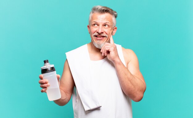 Uomo atleta senior che sorride felicemente e sogna ad occhi aperti o dubita, guardando di lato