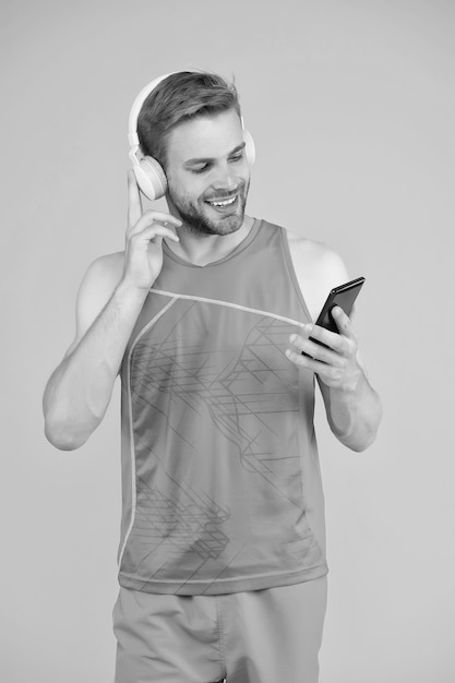 Uomo atletico ascolta musica smartphone Playlist allenamento Sport e fitness Stile di vita attivo Salute e benessere Motivazione allenamento Monitoraggio dei progressi Applicazione per allenamenti con divano online