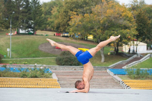 Uomo atletico bello che fa asana di yoga nel parco