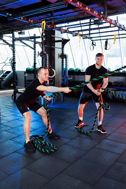 Uomo atletico che fa esercizi con l'aiuto del suo personal trainer in una palestra pubblica.