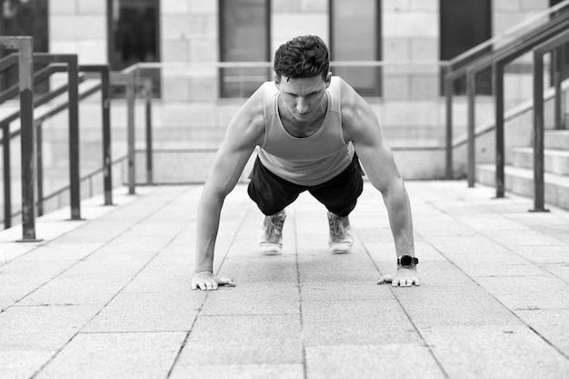 Uomo atletico che fa push up concetto di allenamento urbano