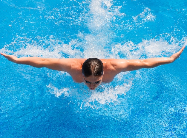 Uomo atletico che nuota nello stile della farfalla della piscina