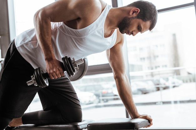 Uomo atletico che si esercita con il manubrio in palestra