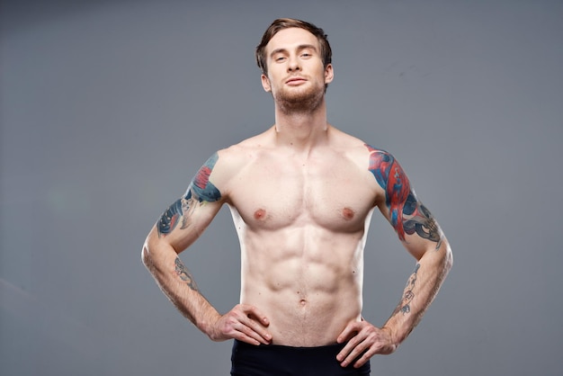Uomo atletico con tatuaggi addominali gonfiati sulle braccia