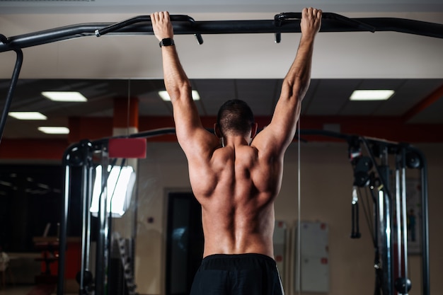 Uomo atletico facendo esercizi di pull-up su una traversa in palestra