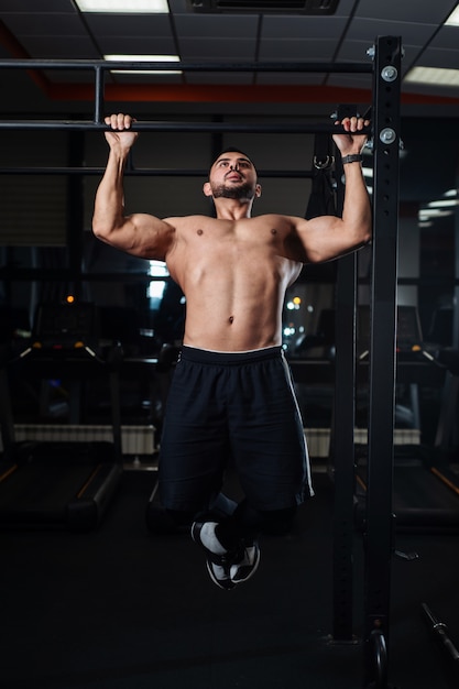 Uomo atletico facendo esercizi di pull-up su una traversa in palestra