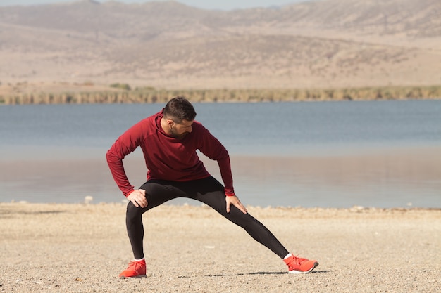 Uomo atletico in abiti sportivi che si estende in natura