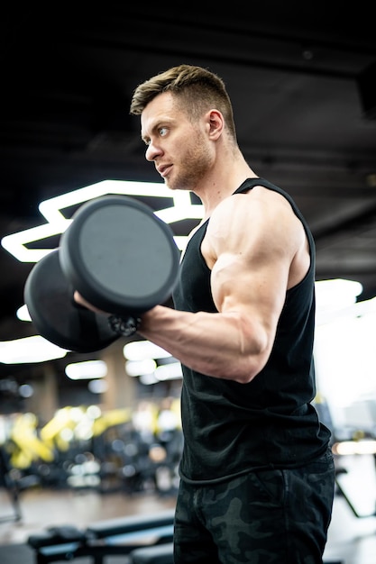 Uomo atletico muscolare che si allena duramente in palestra. Culturista forte bello che fa esercizio.