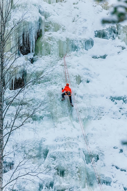 Uomo atletico nella scalata di una grande parete blu di ghiaccio in Finlandia Lapponia