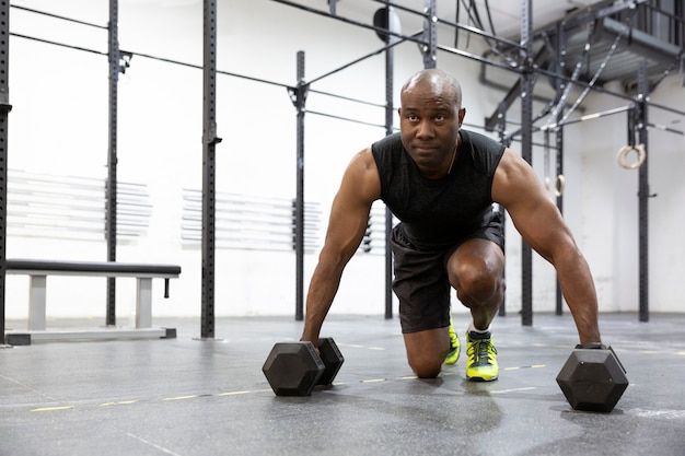 Uomo atletico nero che fa allenamento con i pesi in palestra. Stile di vita sano e sport. Spazio per il testo.