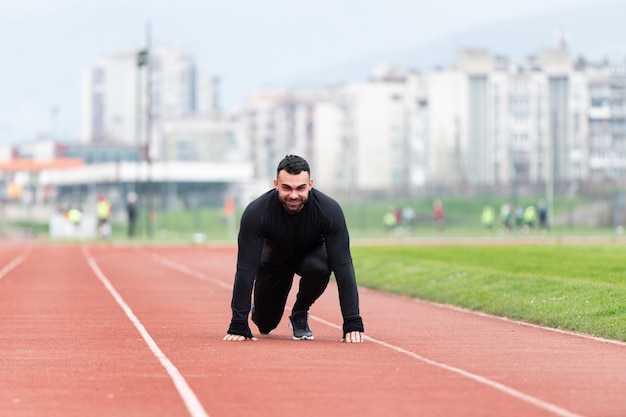 Uomo atletico sulla pista da corsa che si prepara a iniziare a correre